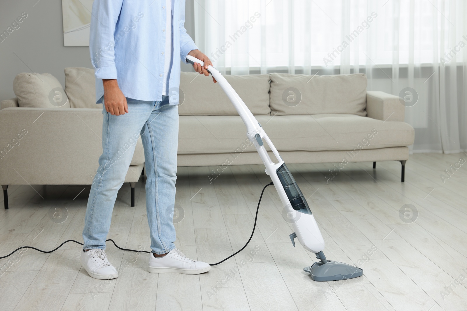 Photo of Man cleaning floor with steam mop at home, closeup