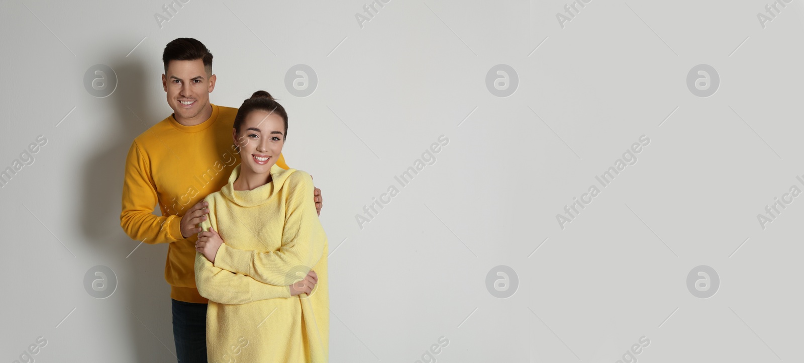 Photo of Happy couple wearing yellow warm sweaters on white background