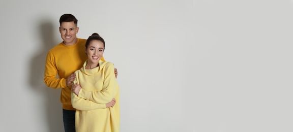 Photo of Happy couple wearing yellow warm sweaters on white background