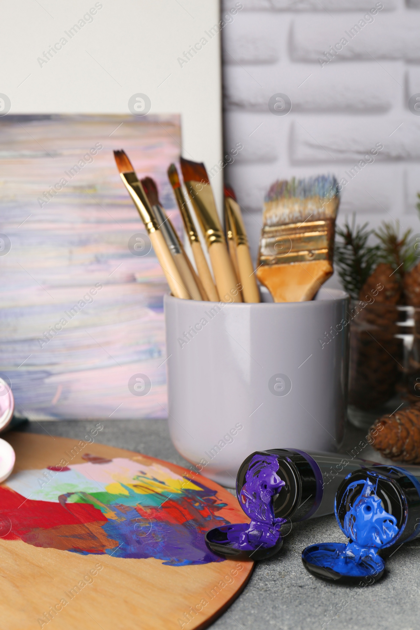 Photo of Artist's palette, tubes of colorful paints and brushes on textured table