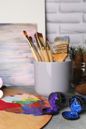 Artist's palette, tubes of colorful paints and brushes on textured table