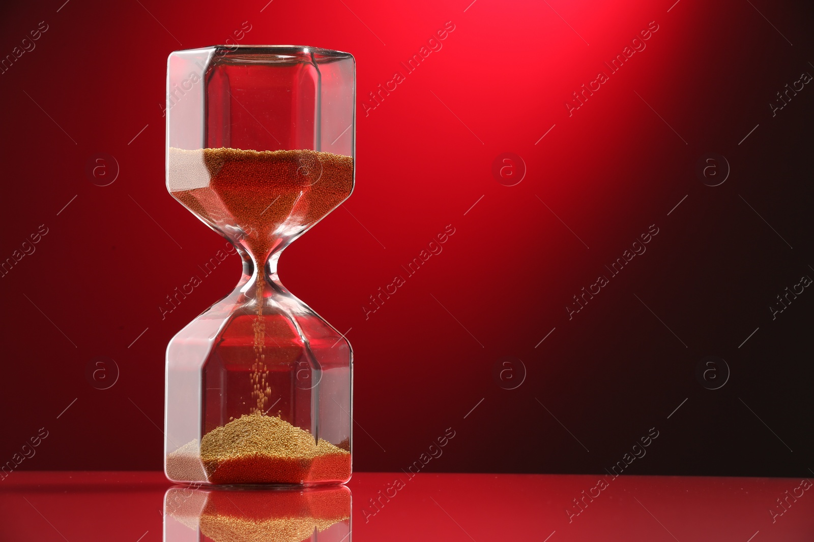 Photo of Hourglass with flowing sand on color background. Space for text