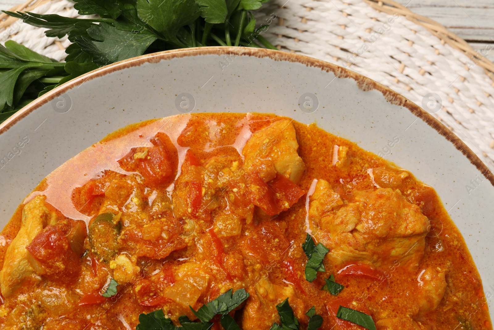 Photo of Delicious chicken curry and parsley on table, top view