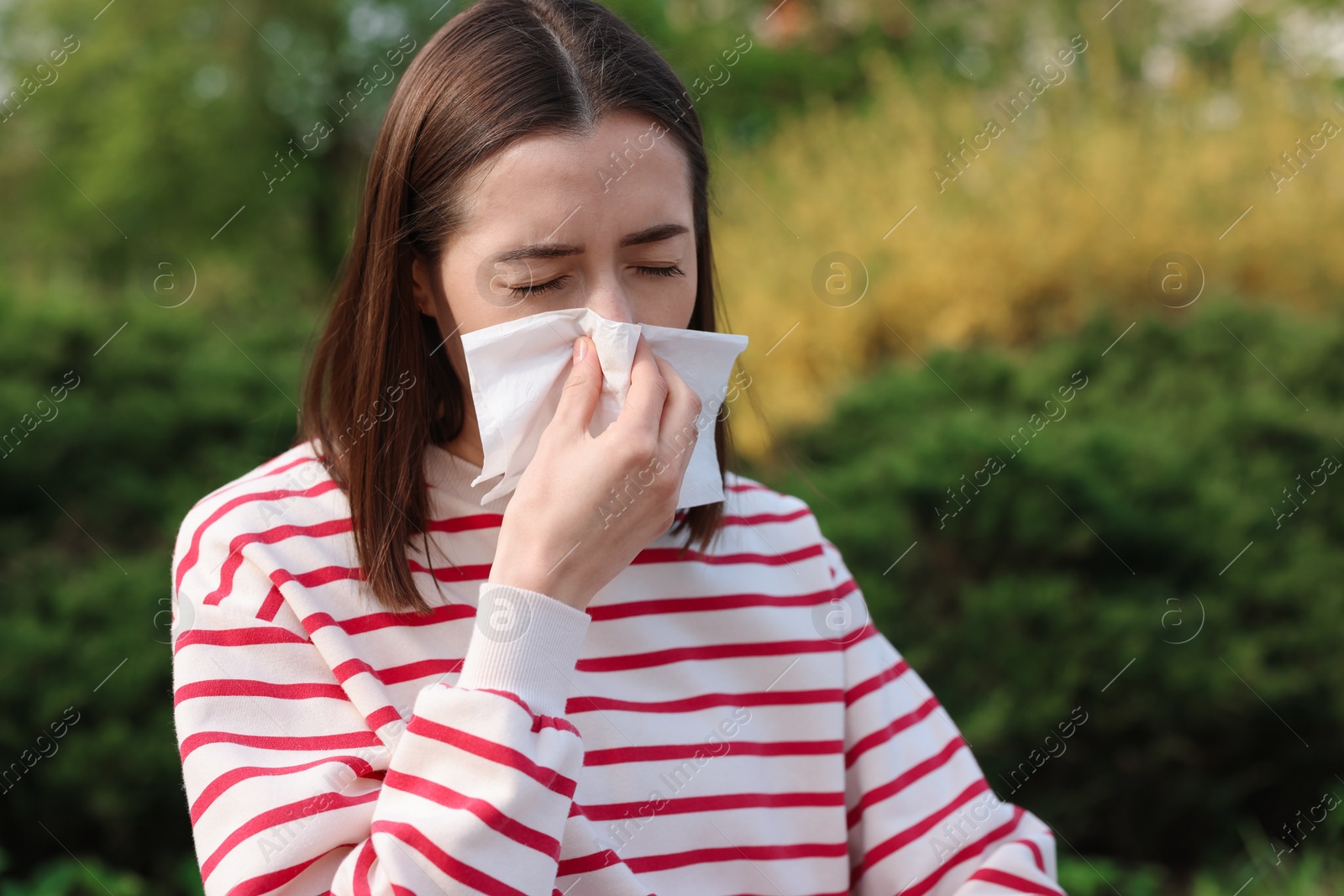 Photo of Woman with napkin suffering from seasonal allergy outdoors