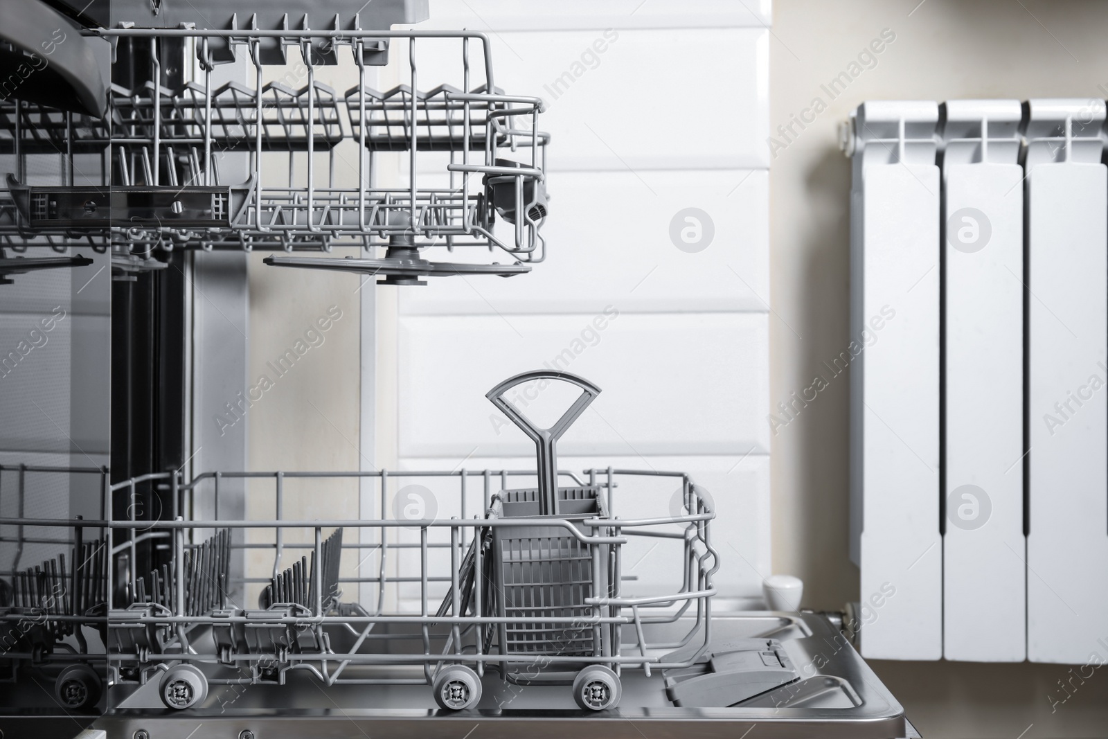 Photo of Open clean modern empty automatic dishwasher machine in kitchen