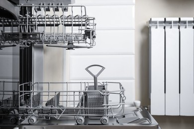 Photo of Open clean modern empty automatic dishwasher machine in kitchen