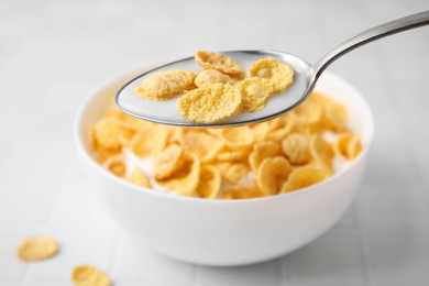 Breakfast cereal. Eating tasty corn flakes with milk at white table, closeup