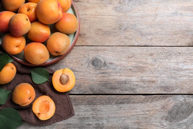 Photo of Delicious fresh ripe apricots on wooden table, flat lay. Space for text