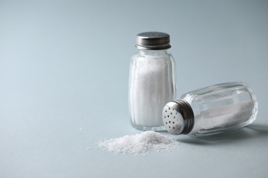 Photo of Natural salt in shakers on color background, space for text