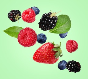 Image of Many different fresh berries falling on light green background