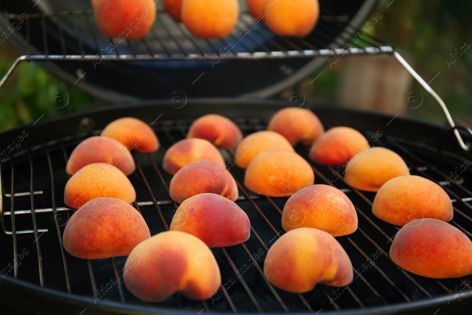 Photo of Modern grill with tasty cut peaches outdoors, closeup