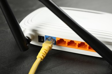 Photo of Modern Wi-Fi router on black table, closeup