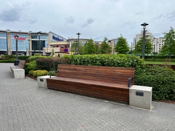 Alley with wooden benches, power sockets and beautiful plants near shopping mall