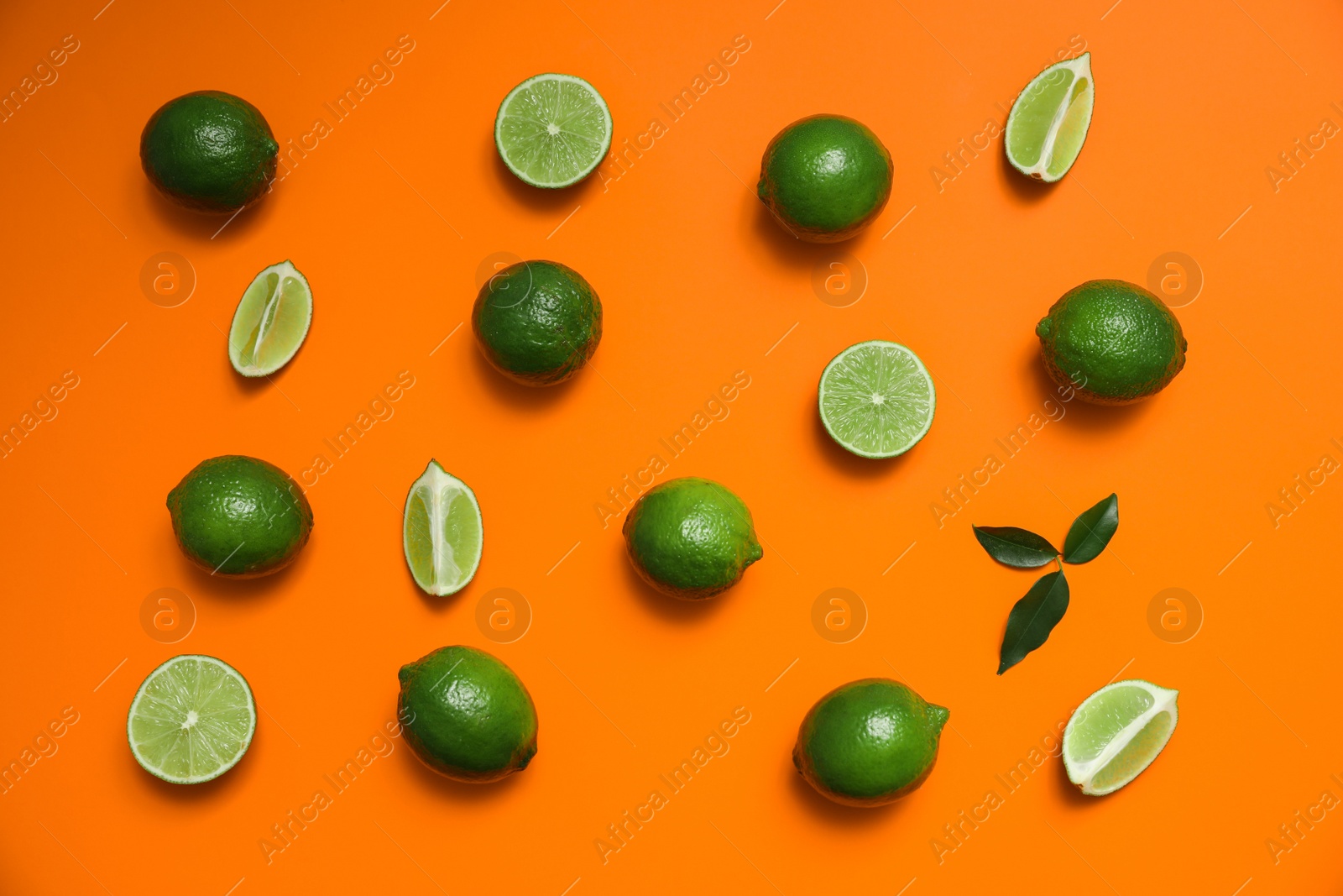 Photo of Flat lay composition with fresh juicy limes on orange background