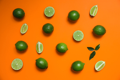 Photo of Flat lay composition with fresh juicy limes on orange background