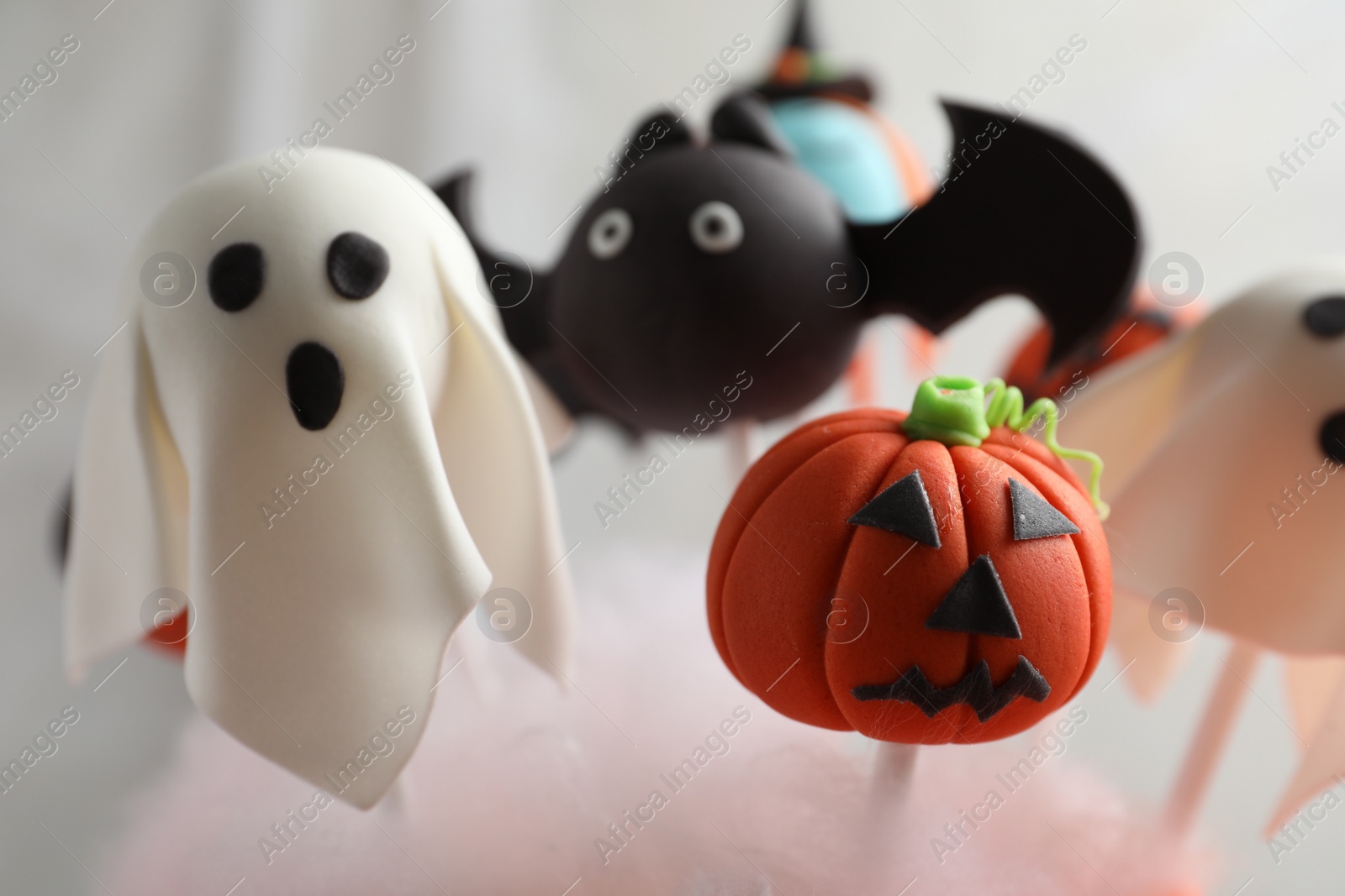 Photo of Different Halloween themed cake pops on light background, closeup