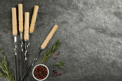 Flat lay composition with metal skewers on grey table. Space for text