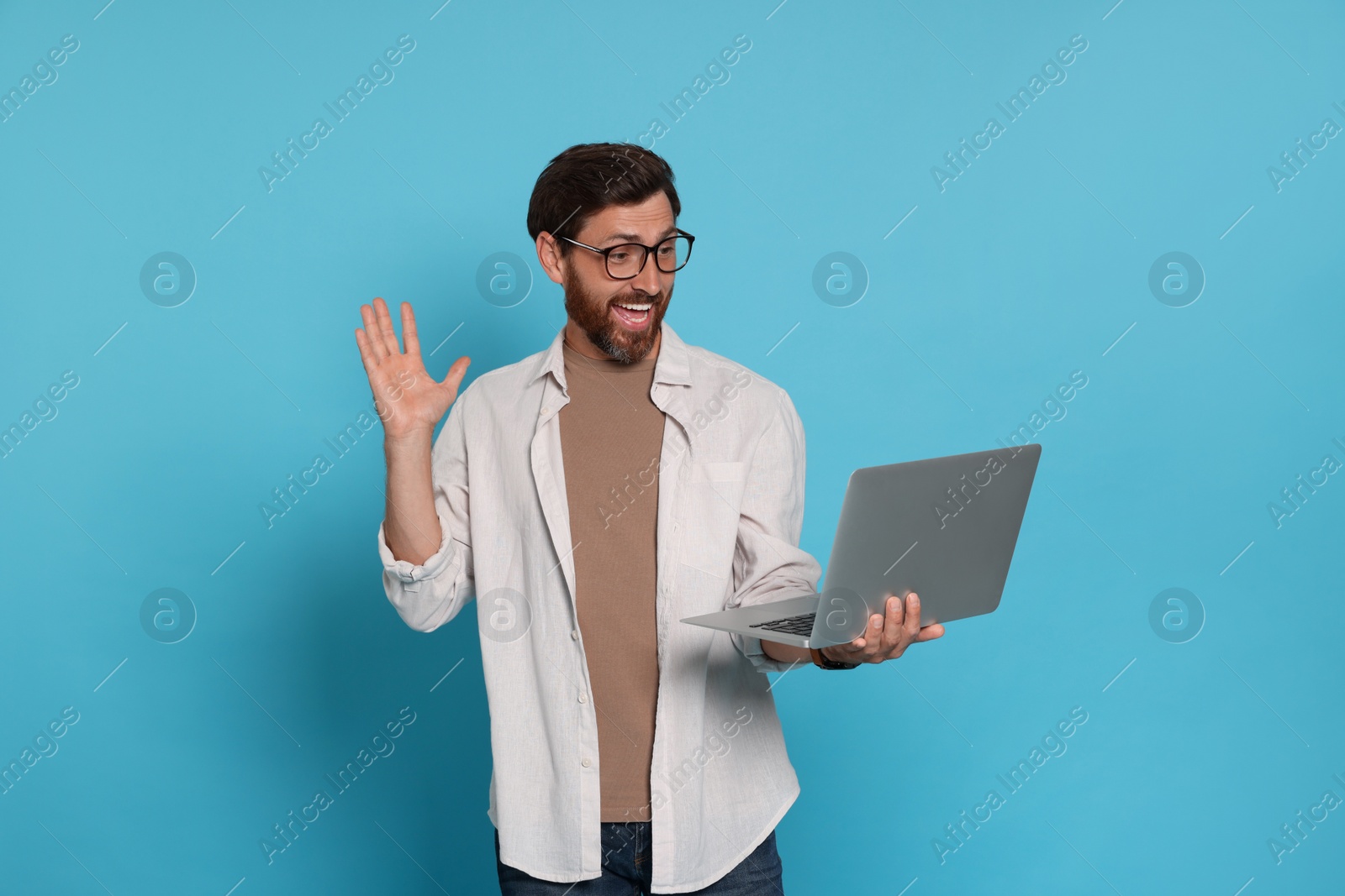 Photo of Handsome man with laptop on light blue background