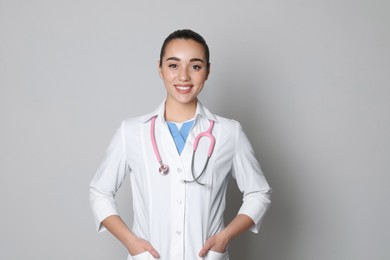 Photo of Portrait of beautiful young doctor on light grey background