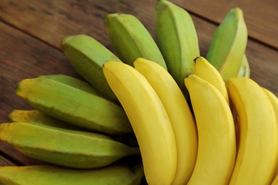 Bunches of tasty bananas on wooden table, closeup