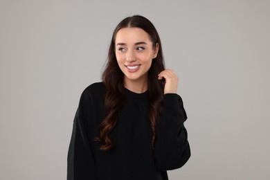 Photo of Beautiful young woman in stylish warm sweater on grey background