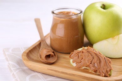 Fresh green apples with peanut butter on table, closeup