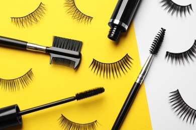 False eyelashes, mascara and brushes on color background, flat lay