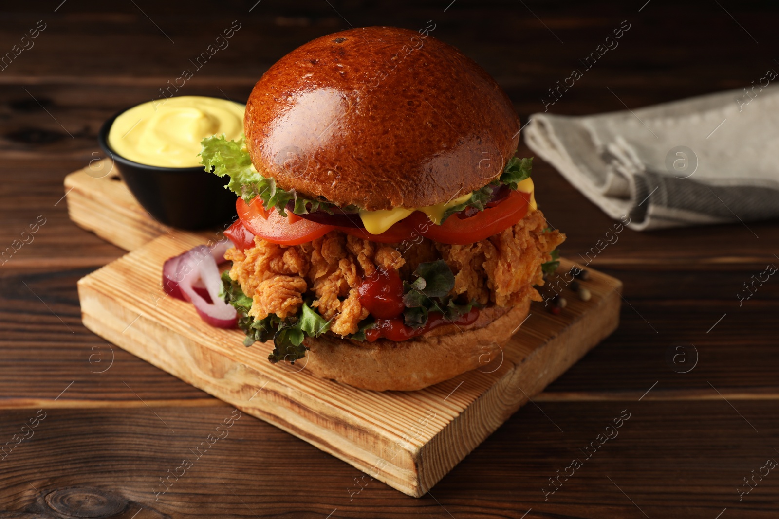 Photo of Delicious burger with crispy chicken patty and sauce on wooden table