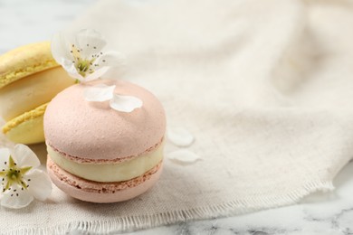 Photo of Delicious colorful macarons and flowers on white marble table. Space for text