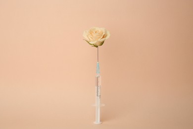 Photo of Medical syringe and rose flower on beige background