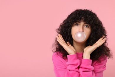 Beautiful young woman blowing bubble gum on pink background. Space for text