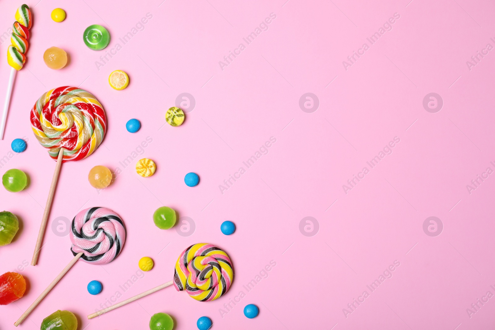 Photo of Bright yummy candies and space for text on color background, top view