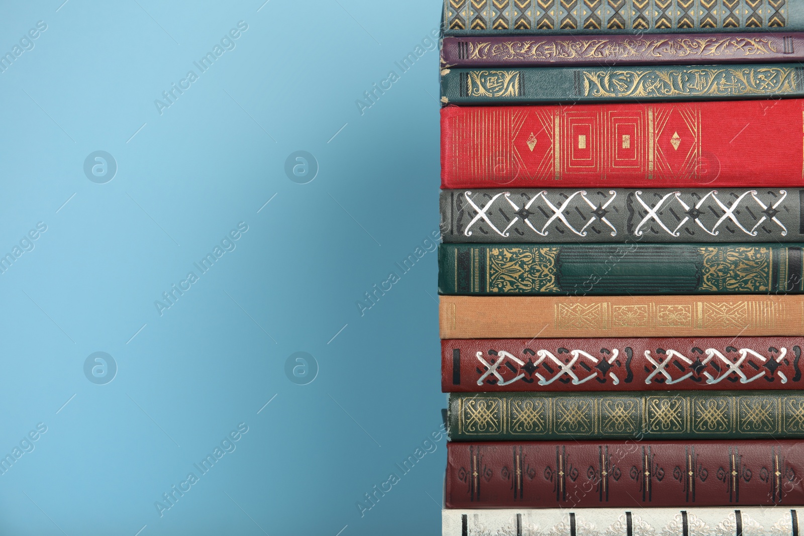 Photo of Stack of hardcover books on light blue background, space for text