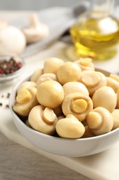 Tasty marinated mushrooms in bowl on wooden table, closeup