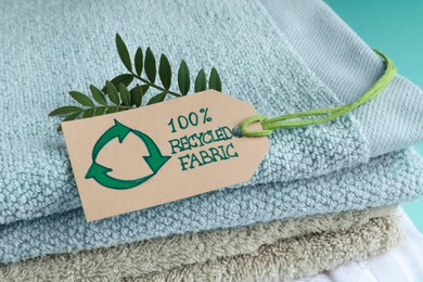 Photo of Stacked towels with recycling label and plant, closeup