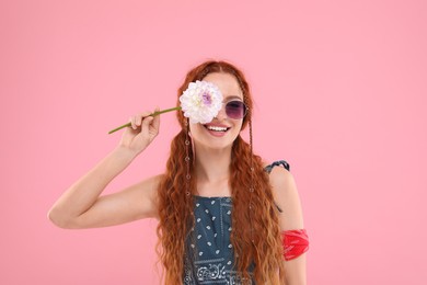 Stylish young hippie woman with dahlia flower on pink background