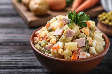 Photo of Delicious salad Olivier on black wooden table, closeup