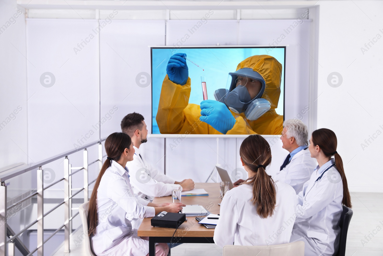 Image of Team of doctors using video projector during coronavirus conference in office