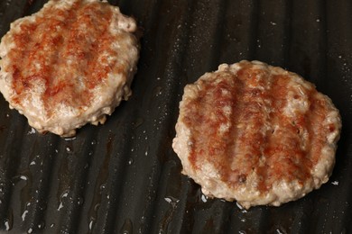 Photo of Cooking tasty hamburger patties on grill pan, closeup