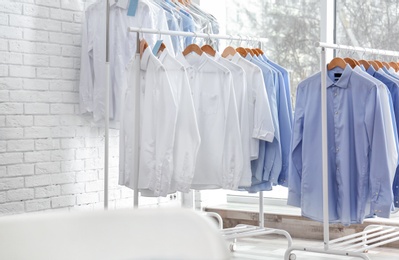 Racks with clean clothes on hangers after dry-cleaning indoors