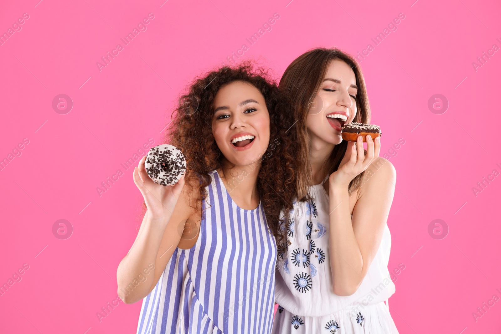 Photo of Beautiful young women with donuts on pink background