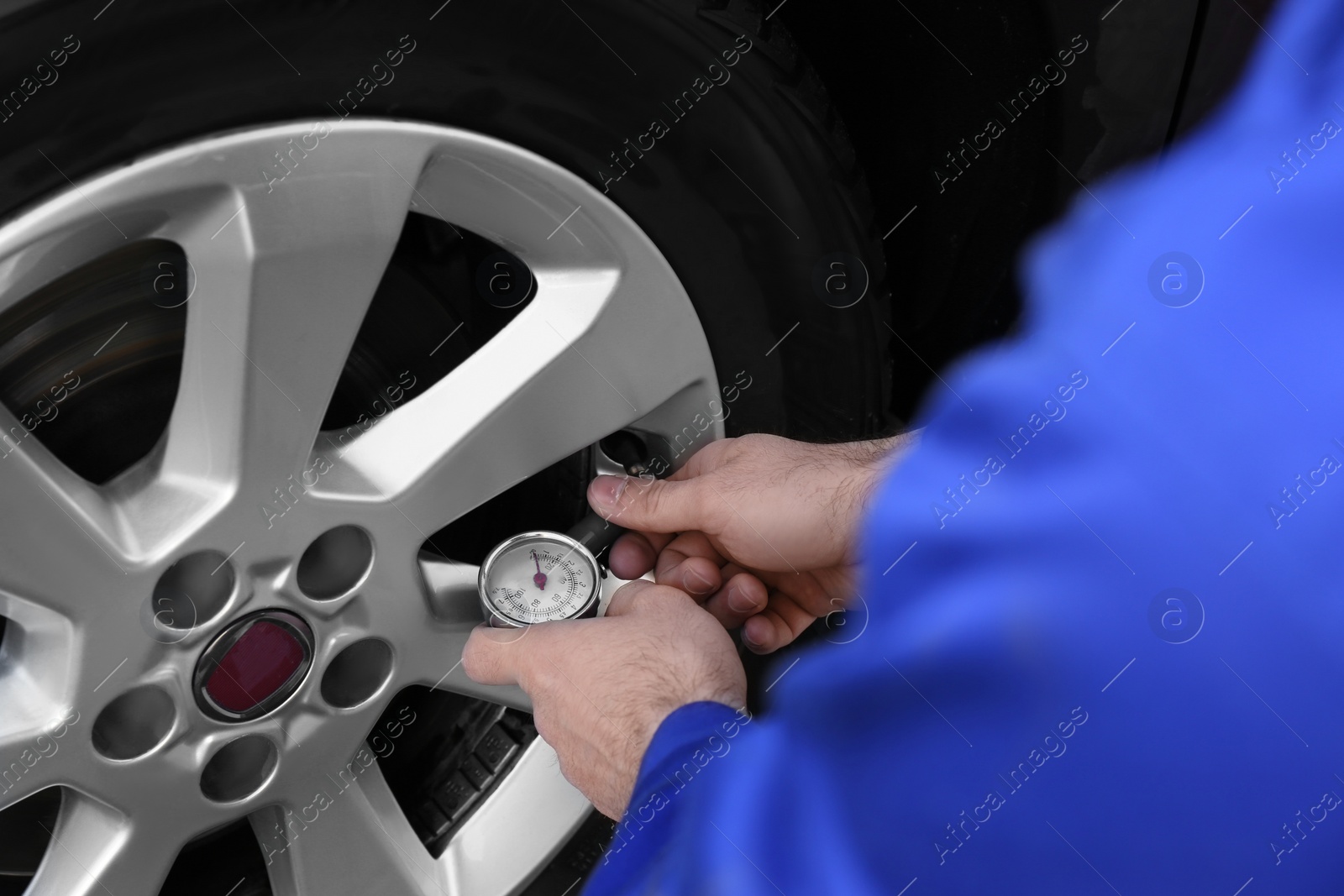 Photo of Mechanic checking tire air pressure at car service, closeup