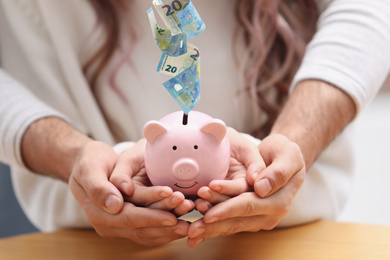Image of Couple with piggy bank at table indoors, closeup