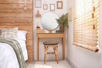 Photo of Stylish dressing table and mirror near white wall in bedroom. Interior design