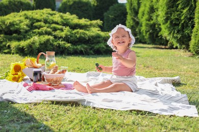 Photo of Cute child sitting on picnic blanket in garden