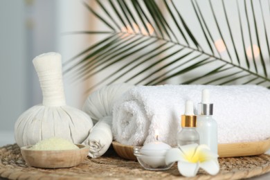 Photo of Composition with different spa products and plumeria flower on wicker mat indoors