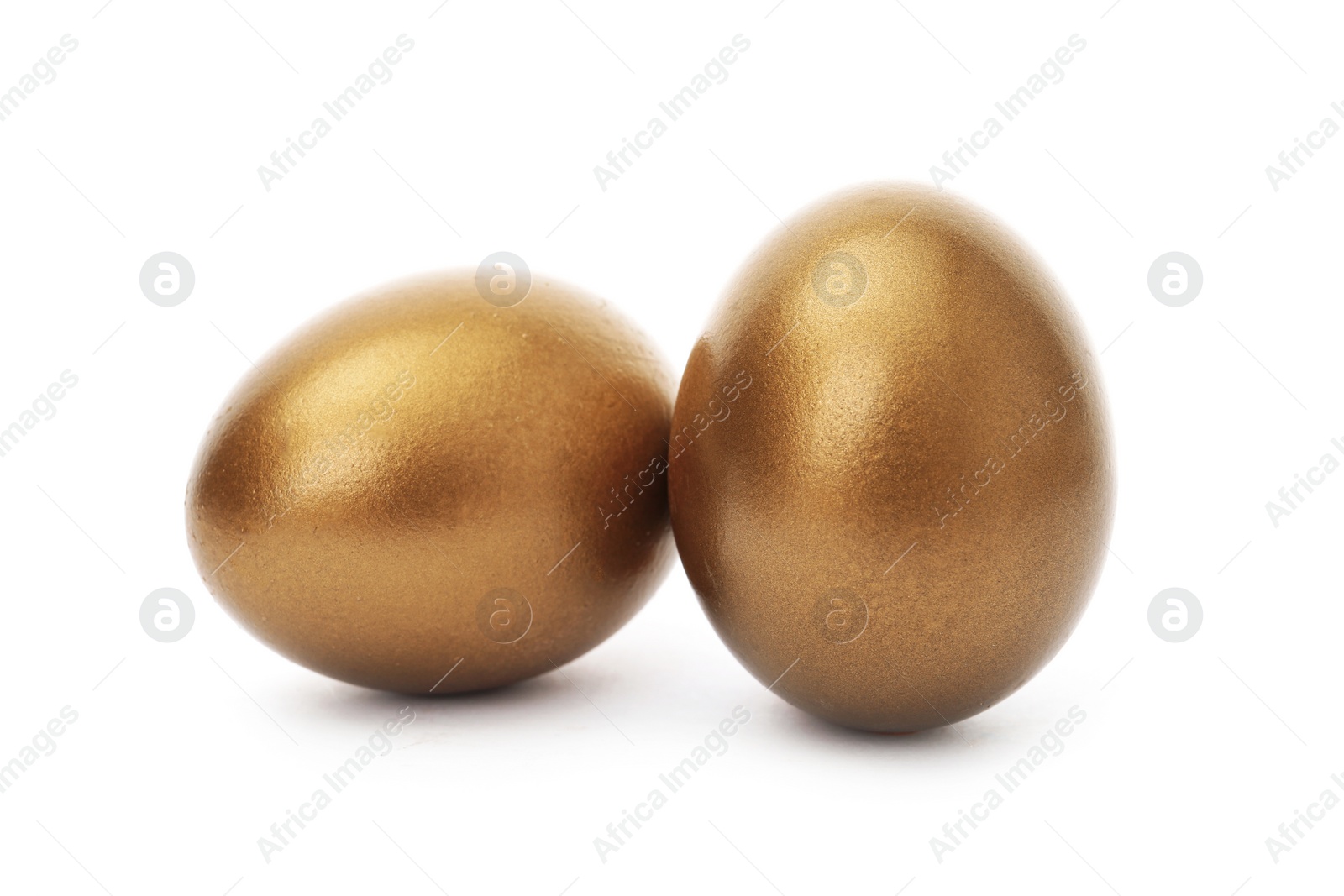 Photo of Two shiny golden eggs on white background