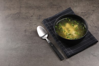 Delicious chicken soup with parsley and spoon on grey table, space for text