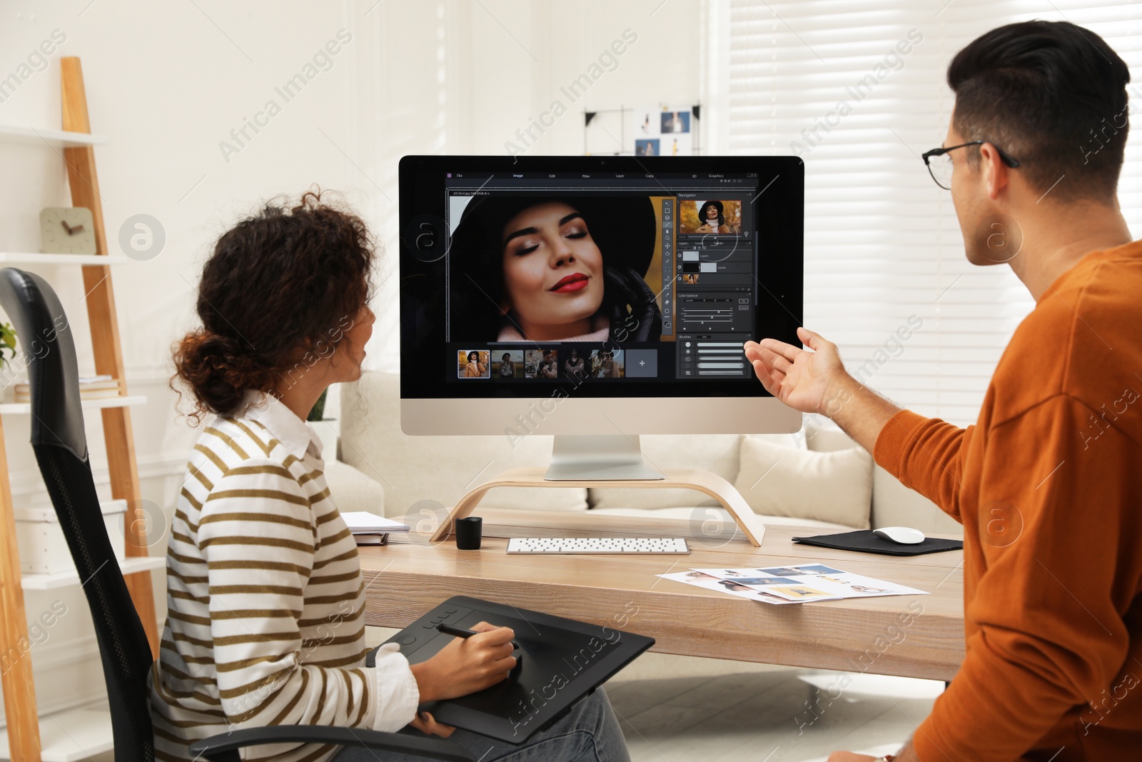 Photo of Professional retoucher with colleague working at desk in office