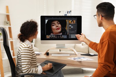 Photo of Professional retoucher with colleague working at desk in office